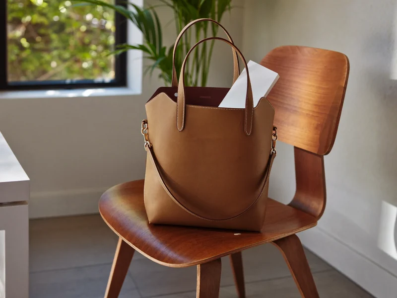 Grosse Naturleder-Tote-Bag auf einem Holzstuhl in einem hellen Büro